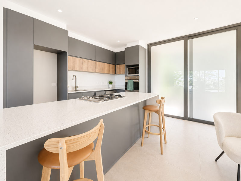 Modern kitchen featuring sleek grey cabinetry, wood-tone accents, quartz countertops, integrated appliances, and large sliding glass doors leading to an outdoor area.