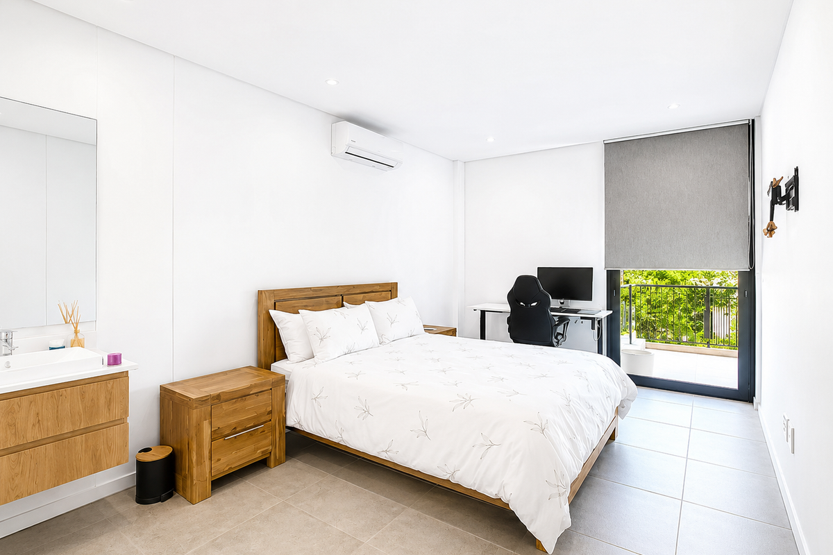 Modern bedroom featuring tiled flooring, recessed lighting, a wall-mounted air conditioning unit, and an integrated vanity with direct access to a private balcony.
