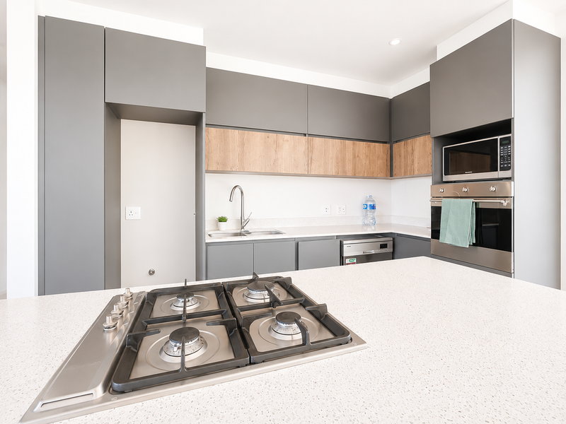 Modern kitchen featuring a central island with a gas cooktop, integrated appliances, quartz countertops, and sleek two-tone cabinetry.