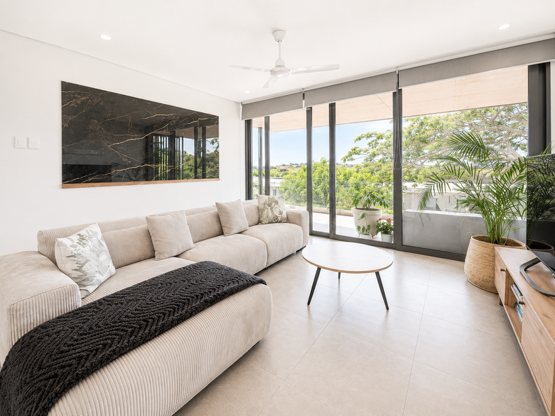 Modern living room featuring large sliding glass doors, tiled flooring, recessed lighting, and a decorative marble wall panel, offering a bright and contemporary space.