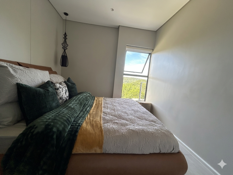 A well-maintained bedroom featuring neutral walls, recessed ceiling lighting, and a window offering natural light and scenic views.