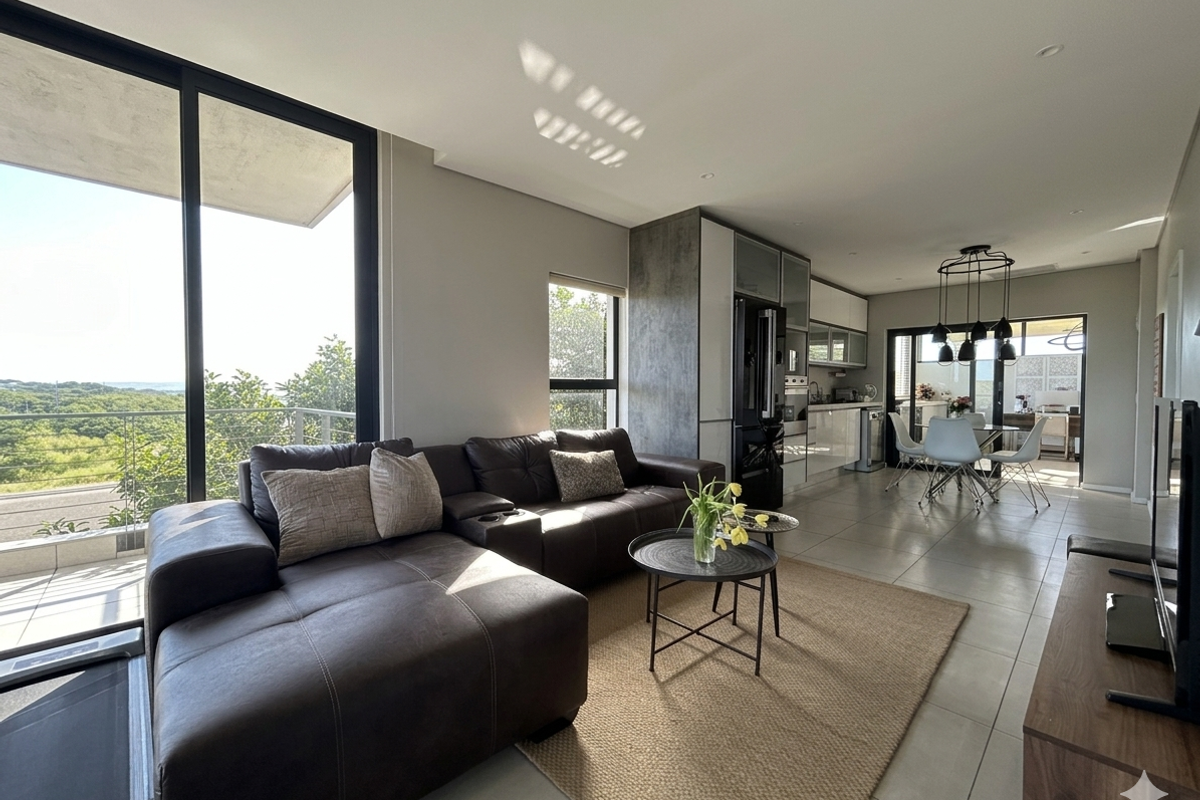 Modern open-plan living and kitchen area featuring sleek cabinetry, integrated appliances, large sliding glass doors, and abundant natural light with scenic views.