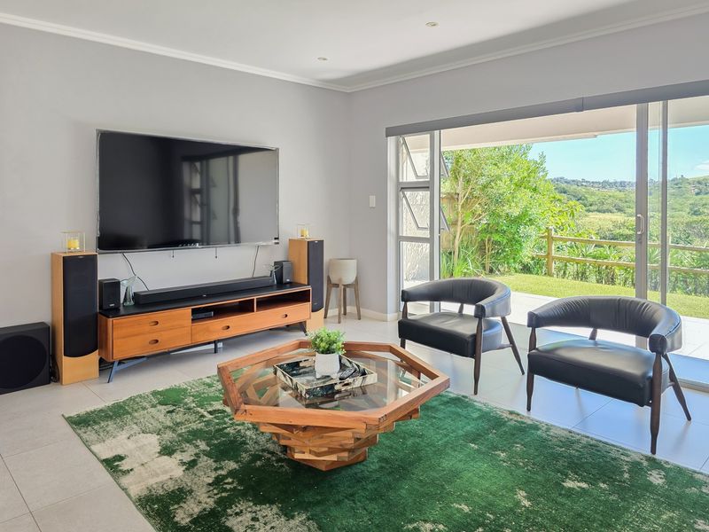 Bright living room featuring large sliding glass doors that open to a scenic outdoor area, complemented by neutral walls and modern tiled flooring.