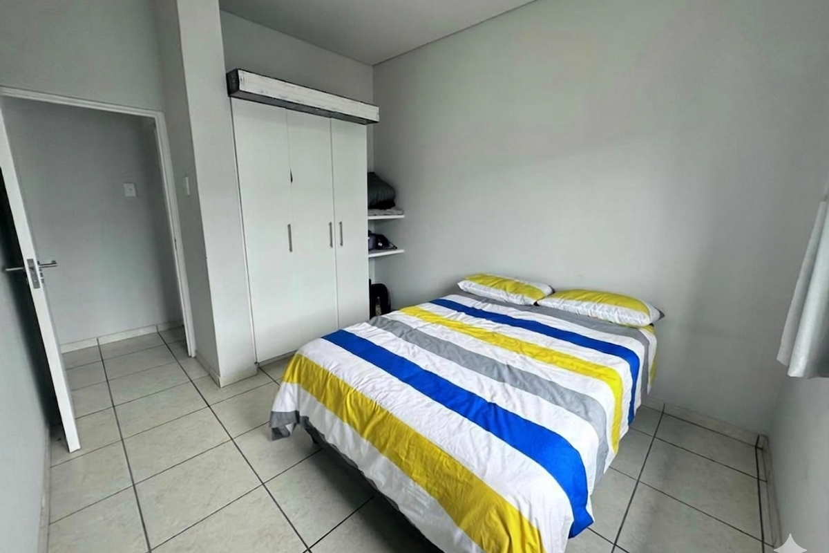 A functional bedroom featuring neutral wall finishes, tiled flooring, and a built-in wardrobe for storage.