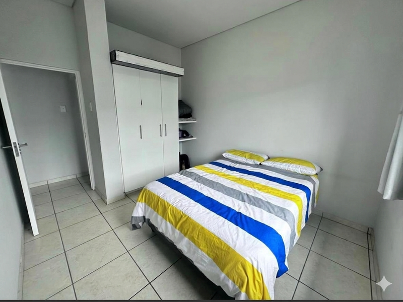 A functional bedroom featuring neutral wall finishes, tiled flooring, and a built-in wardrobe for storage.