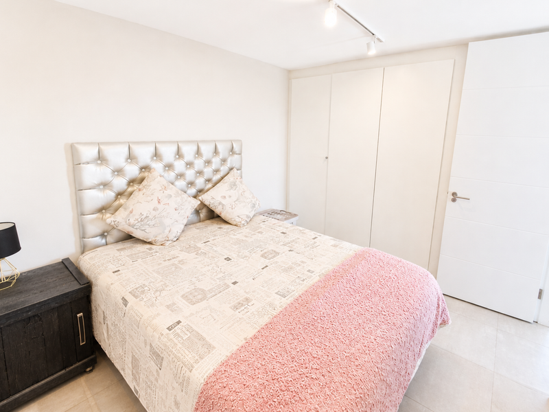 A well-maintained bedroom featuring neutral tiled flooring, built-in wardrobe storage, and modern track lighting.