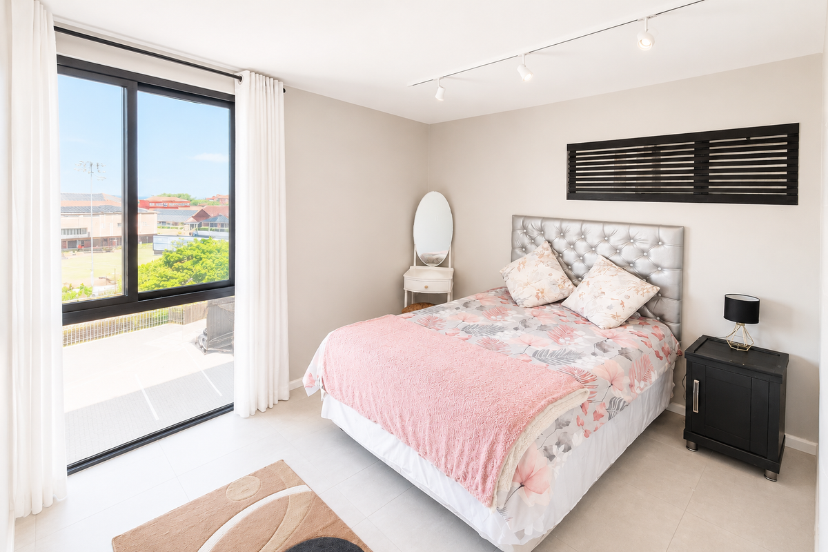 A bright and modern bedroom featuring large sliding glass doors, neutral tiled flooring, and contemporary track lighting.