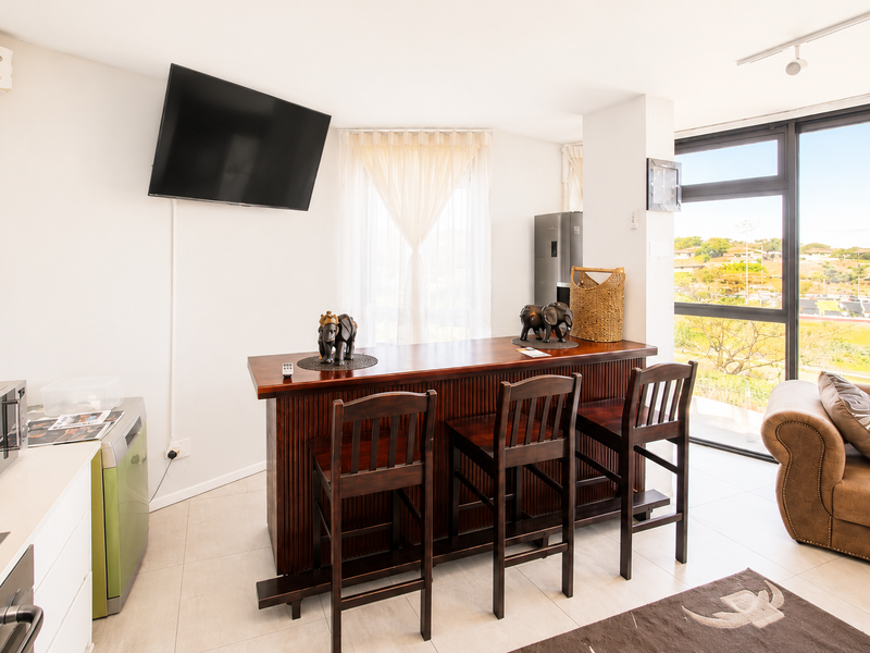 Open-plan living and kitchen area featuring tiled floors, modern cabinetry, and large windows with expansive views.