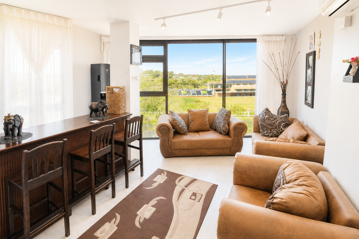 A bright, open-plan living area featuring large windows with scenic views, tiled flooring, and integrated air conditioning.