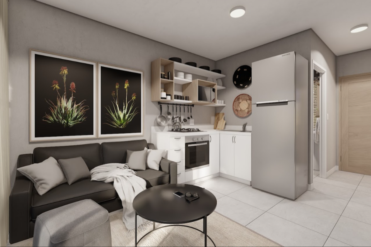 Modern open-plan living area featuring a compact kitchen with built-in oven, gas hob, and clean white cabinetry, seamlessly integrated with the living space.