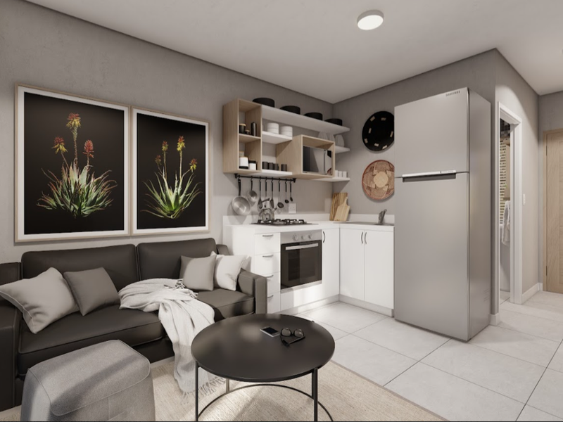 Modern open-plan living area featuring a compact kitchen with built-in oven, gas hob, and clean white cabinetry, seamlessly integrated with the living space.