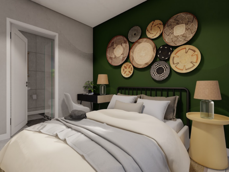 A modern bedroom featuring a dark green accent wall, tiled flooring, and an adjoining en-suite bathroom with a glass shower enclosure.