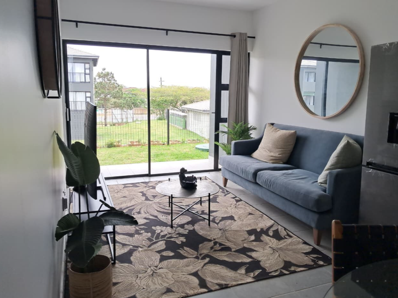 A bright living room featuring large sliding glass doors that provide access to the outdoor area and allow for ample natural light.