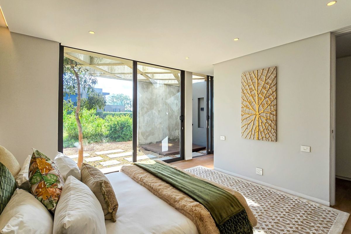 Modern bedroom featuring floor-to-ceiling sliding glass doors, recessed lighting, and built-in storage, offering seamless access to the outdoor garden area.