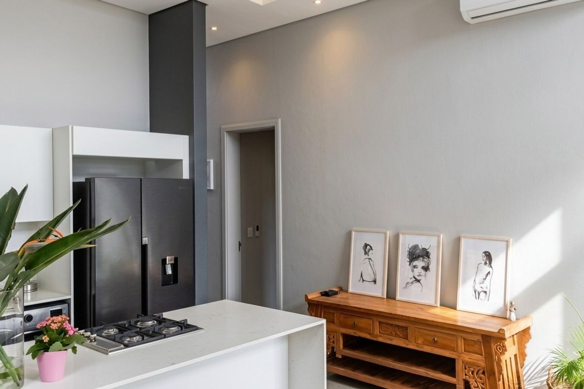 Modern kitchen featuring a stone-topped island with an integrated gas hob, sleek white cabinetry, and recessed lighting in a contemporary open-plan setting.