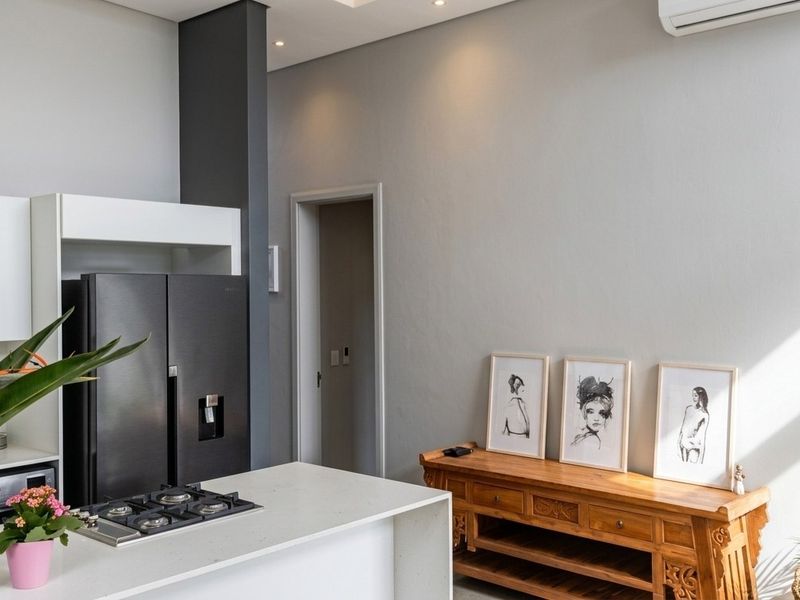 Modern kitchen featuring a stone-topped island with an integrated gas hob, sleek white cabinetry, and recessed lighting in a contemporary open-plan setting.