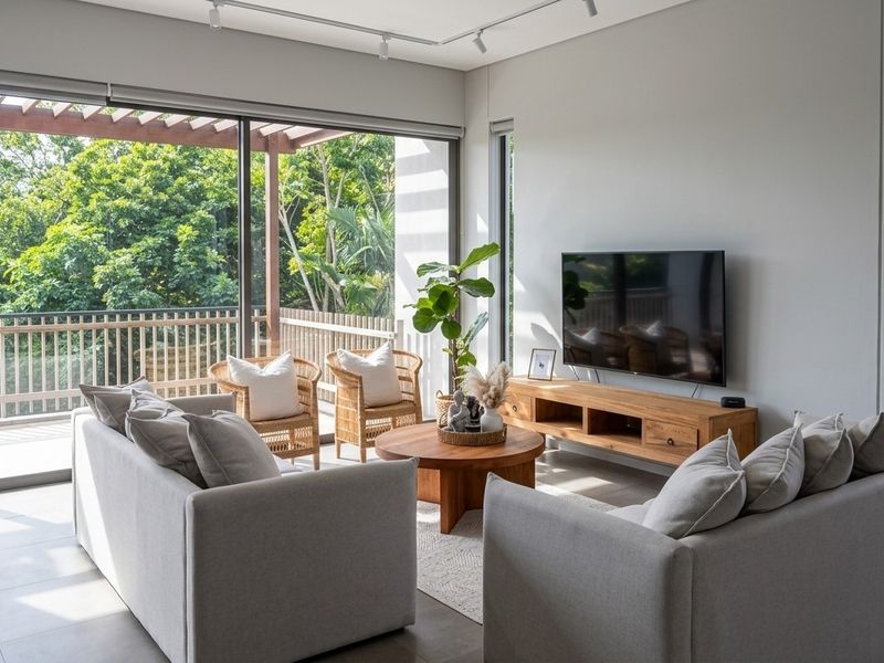 Modern living room featuring large sliding glass doors that open onto a covered balcony with a pergola, offering natural light and scenic views.