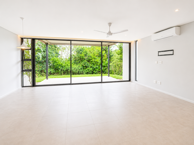 Spacious, modern open-plan living area featuring large sliding glass doors that open to a private garden, tiled floors, and integrated climate control.
