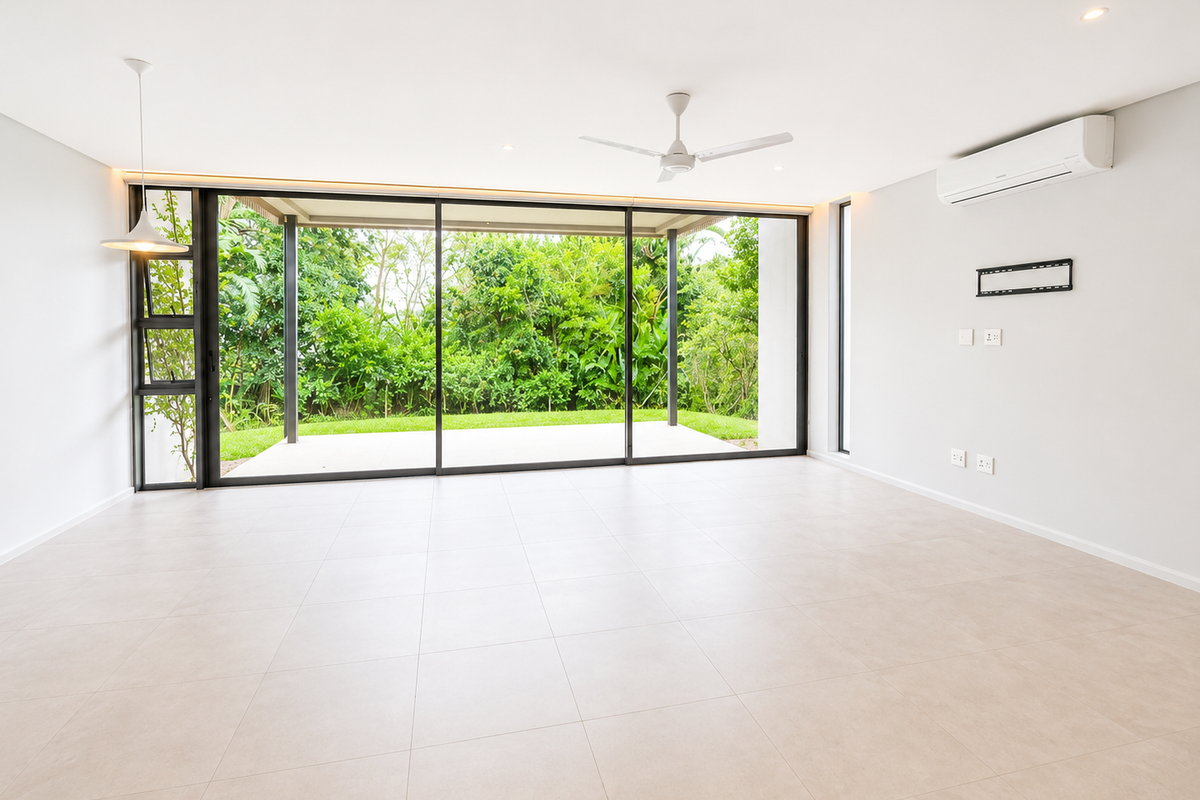 Spacious, modern open-plan living area featuring large sliding glass doors that open to a private garden, tiled floors, and integrated climate control.