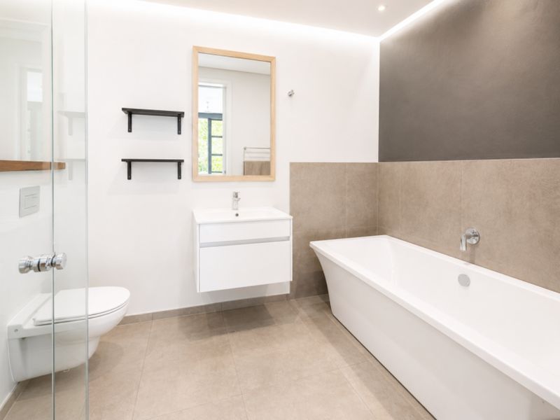 Modern bathroom featuring a floating vanity, freestanding bathtub, wall-mounted toilet, and glass shower enclosure with contemporary neutral tiling and recessed lighting.