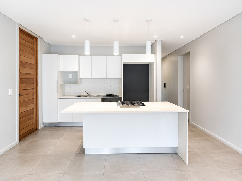 Modern kitchen featuring a central island with a gas cooktop, sleek white cabinetry, tiled flooring, and contemporary pendant lighting in an open-plan layout.