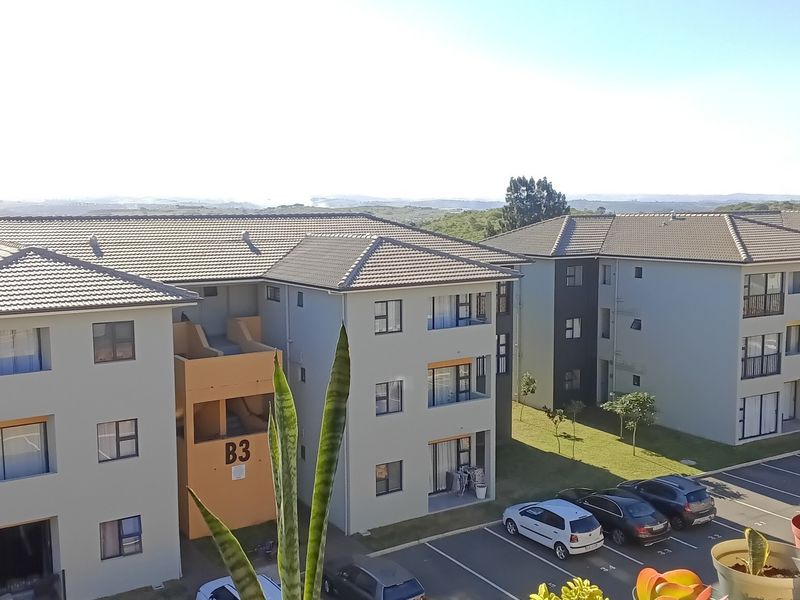 Exterior view of a modern apartment complex featuring tiled roofs, concrete facades, and designated parking bays.