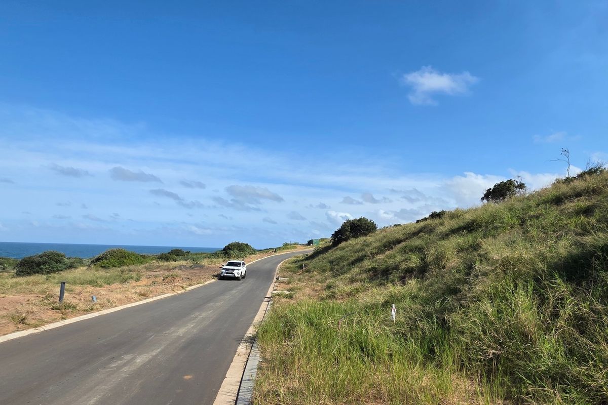 A view of the paved access road leading through the vacant residential land, featuring coastal landscape surroundings.