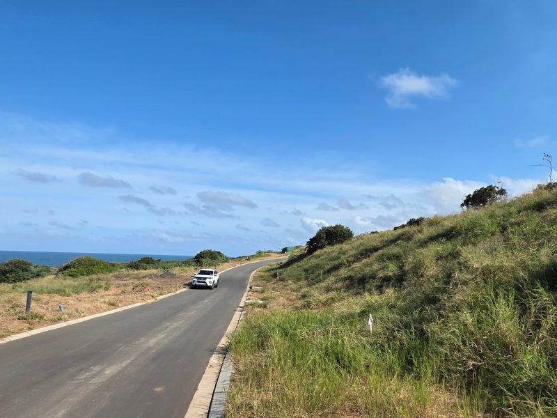 A view of the paved access road leading through the vacant residential land, featuring coastal landscape surroundings.