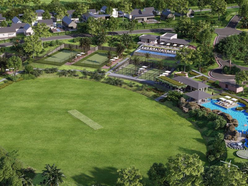 An aerial view of a residential estate featuring a cricket pitch, tennis courts, swimming pools, and clubhouse facilities within a landscaped environment.