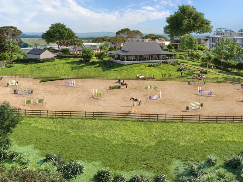 Aerial view of a professional equestrian arena with post and rail fencing, set within a landscaped estate featuring a clubhouse.