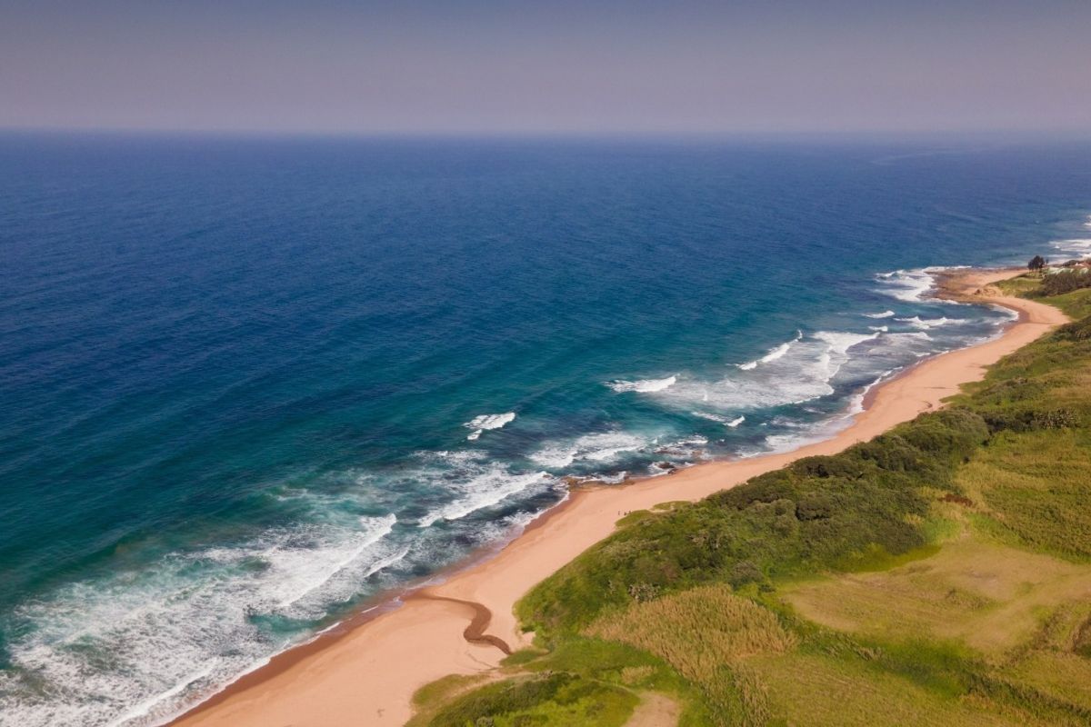 An aerial view of the pristine coastline, featuring sandy beaches and natural vegetation, highlighting the scenic location of the vacant land.