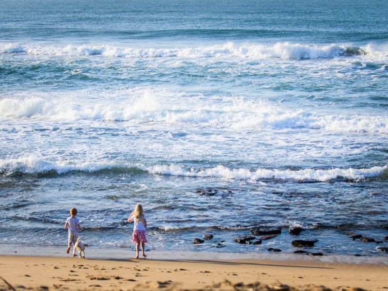 A scenic view of the ocean waves crashing onto the sandy beach shoreline.
