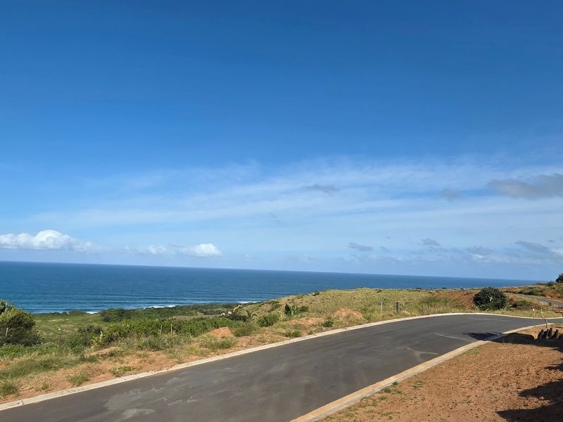A scenic view of the coastline featuring a paved access road leading through the vacant residential land.