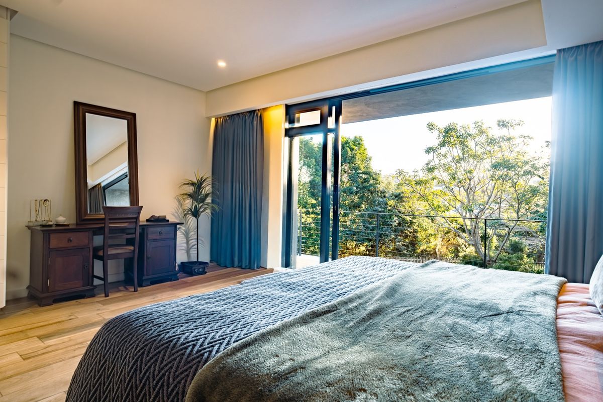 Spacious bedroom featuring hardwood flooring, recessed lighting, and large sliding glass doors opening onto a private balcony with scenic views.