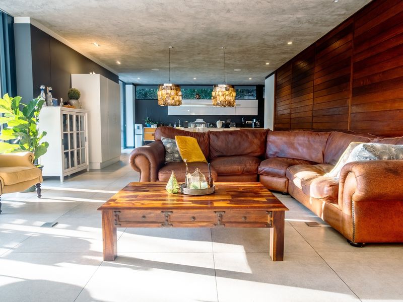 Spacious open-plan living area featuring large format floor tiles, warm timber wall paneling, and a modern kitchen with integrated cabinetry and stylish pendant lighting.