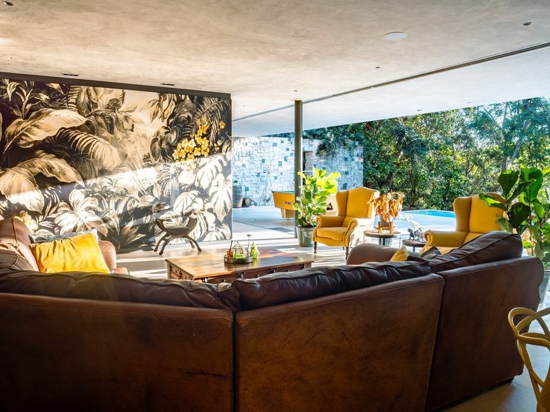 Spacious open-plan living area featuring large sliding glass doors that seamlessly connect to the outdoor patio and pool area, enhanced by stylish feature wallpaper.