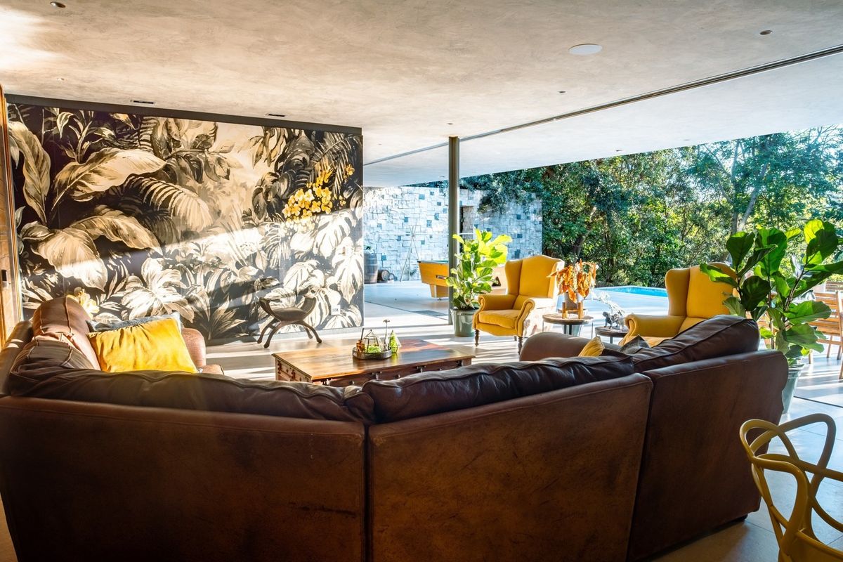 Spacious open-plan living area featuring large sliding glass doors that seamlessly connect to the outdoor patio and pool area, enhanced by stylish feature wallpaper.
