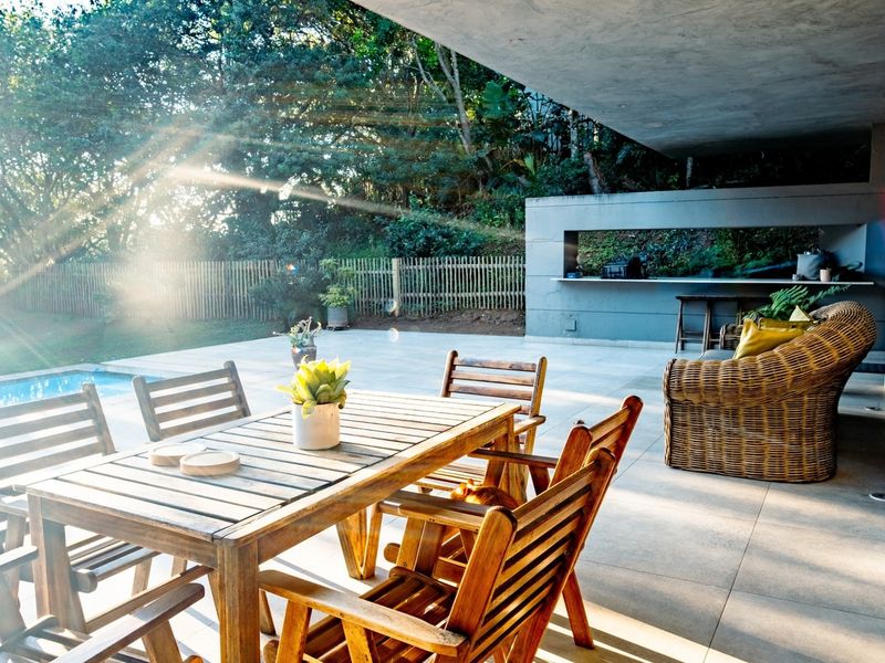 A spacious covered patio featuring a built-in outdoor counter, tiled flooring, and direct access to a swimming pool, perfect for outdoor entertaining.