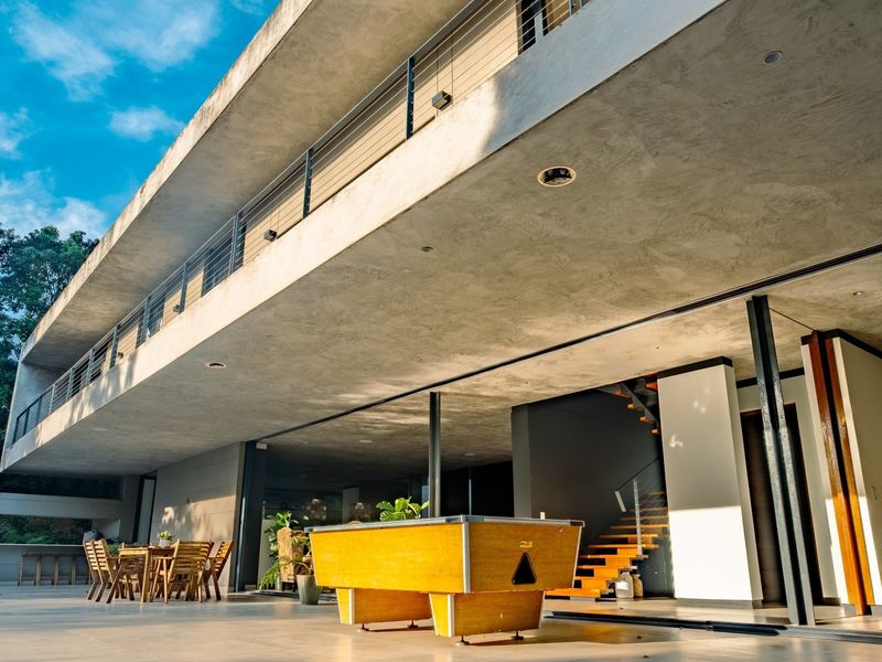 Spacious covered patio featuring a concrete ceiling with recessed lighting, tiled flooring, and seamless access to the interior through large sliding glass doors.