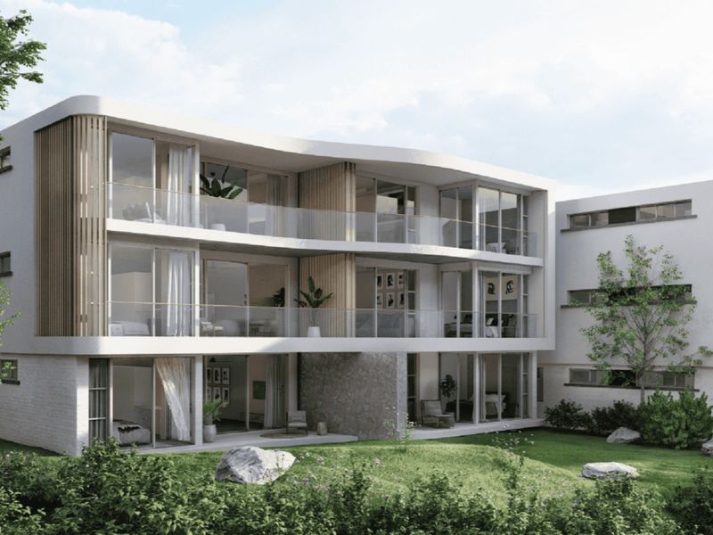 A modern apartment building exterior featuring contemporary architectural design, glass balconies, stone accents, and landscaped garden areas.