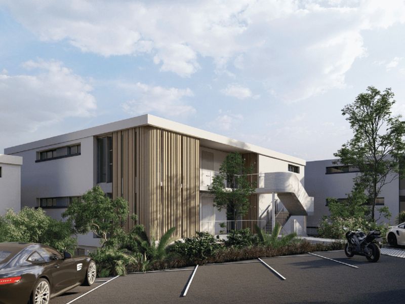 A modern apartment complex exterior featuring contemporary timber slat cladding, a concrete staircase, and dedicated asphalt parking spaces.