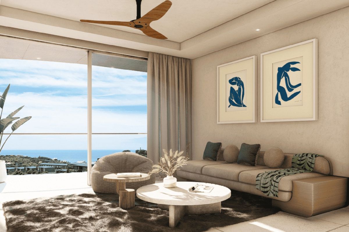 A modern living room featuring a ceiling fan, recessed lighting, and large sliding glass doors that open to a scenic coastal view.