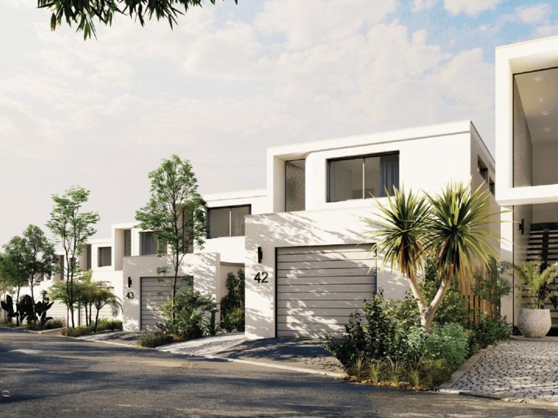 A modern townhouse exterior featuring a clean architectural facade, integrated garage, and landscaped front approach.