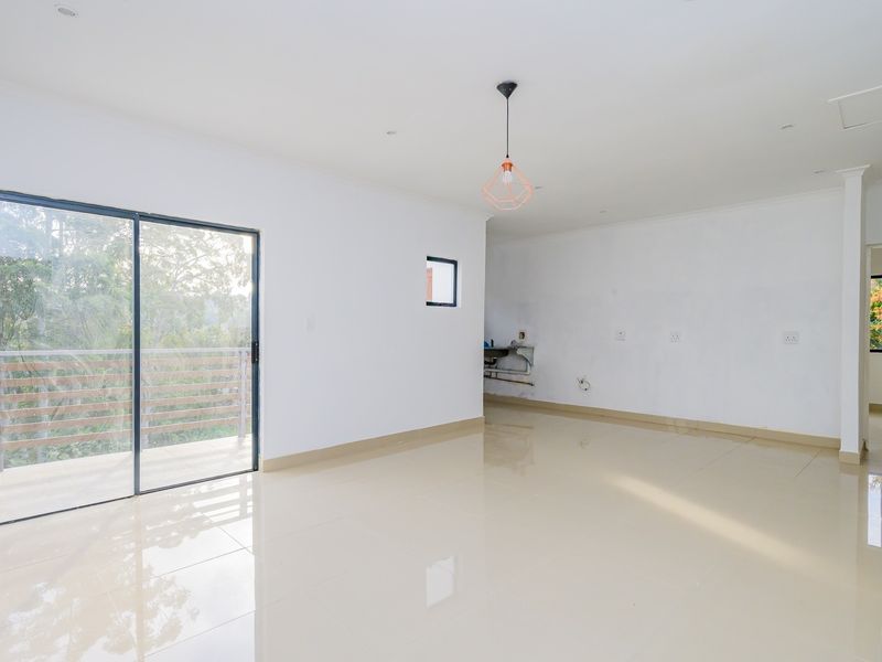 Spacious open-plan living area featuring polished floor tiles, modern lighting, and sliding door access to a private balcony.