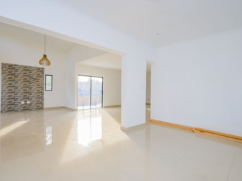Spacious open-plan living area featuring polished tile flooring, a decorative stone feature wall, and large sliding glass doors leading to an outdoor space.