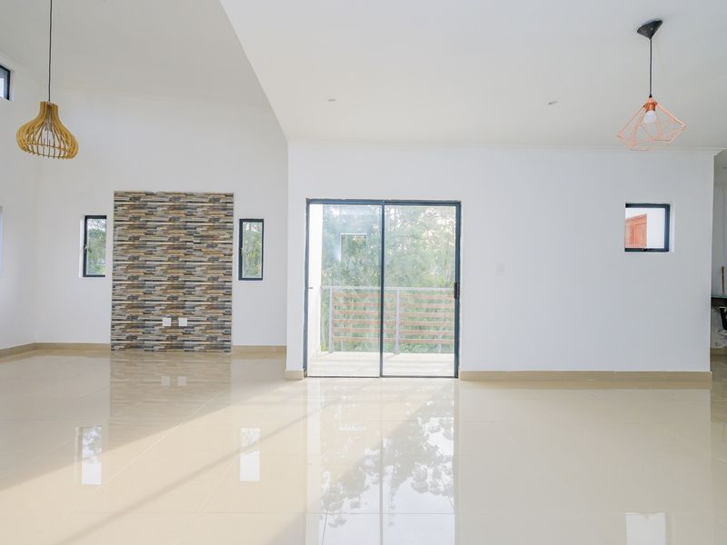 Spacious open-plan living area featuring polished porcelain tiles, a stone feature wall, and large sliding glass doors leading to an outdoor balcony.