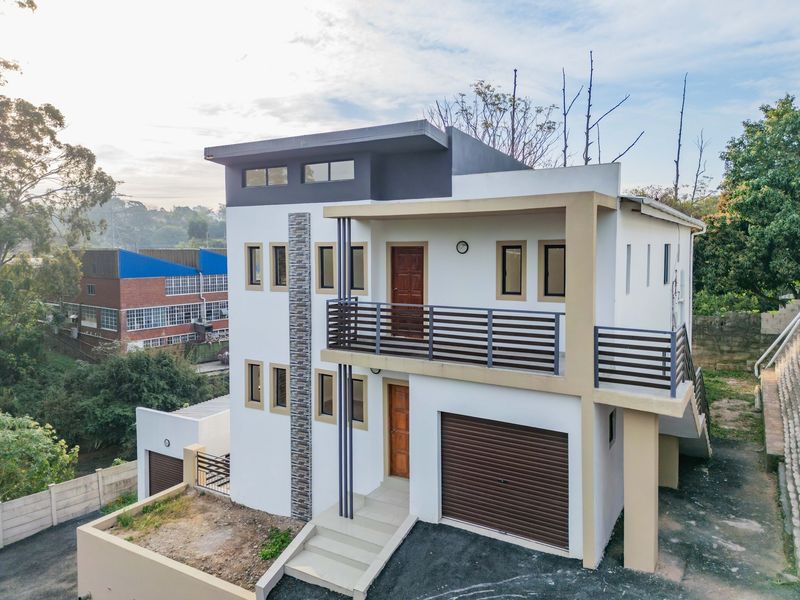A modern multi-story apartment building featuring a garage, a private balcony with railings, and contemporary stone cladding accents.