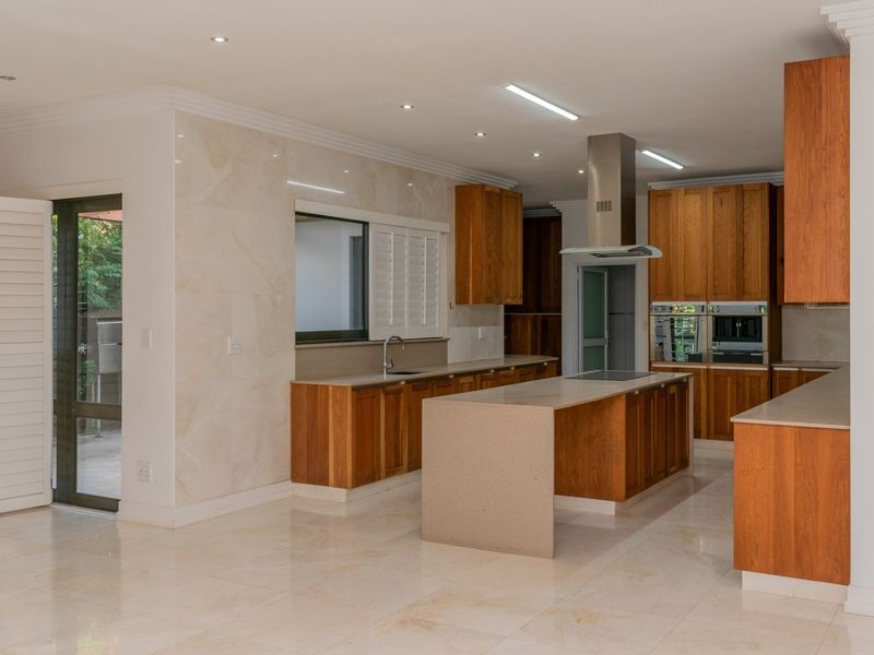 Spacious modern kitchen featuring high-quality wooden cabinetry, stone countertops, a central island, built-in appliances, and polished marble-look flooring.