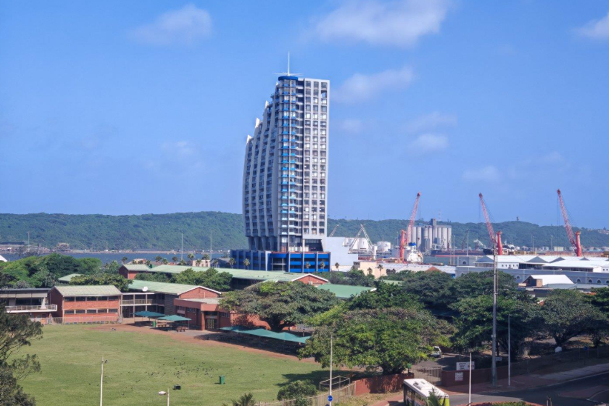 An elevated view of the surrounding urban landscape, featuring a prominent high-rise building and nearby harbour industrial area.
