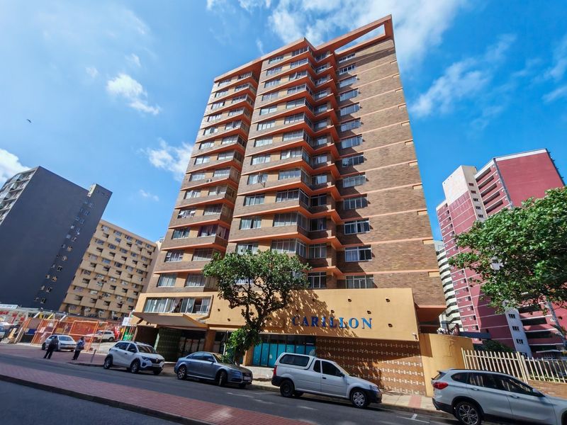 Street-level view of the Carillon apartment building, featuring a multi-story brick facade with integrated balconies and ground-floor entrance.